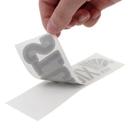 Hand peeling white paper from a decal.