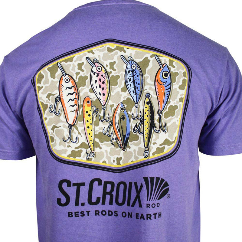 Close-up of a purple t-shirt, showing the back with a large graphic of seven fishing lures inside a camouflage emblem, with the text 'ST. CROIX ROD' printed below.
