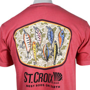 Close-up of a coral red t-shirt, showing the back with a large graphic of seven fishing lures inside a camouflage emblem, with the text 'ST. CROIX ROD' printed below.