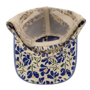 Underside of a baseball cap featuring a beige mesh back and a curved brim with a blue, green, and yellow floral pattern.